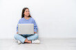 © luismolinero - Young caucasian woman with laptop sitting on the floor isolated on white background looking side