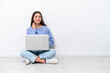 © luismolinero - Young caucasian woman with laptop sitting on the floor isolated on white background thinking an idea