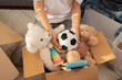 Teenager sorting and collect kid toys, clothes into boxes at home. Donations for charity, help low income families, declutter home, sell online, moving into new home, recycling, sustainable living