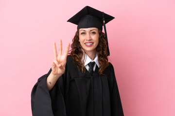 Wall Mural - Young university graduate woman isolated on pink background happy and counting three with fingers