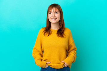 Wall Mural - Redhead girl isolated on blue background thinking an idea while looking up