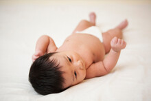 Newborn Asian Baby In Diaper Lying On Back, Scratching Head From Baby Acne, Studio Shot On White Background