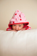 Portrait Of Two Week Old, Newborn Asian Baby Girl In Pink Polka Dot Hooded Jacket, Studio Shot On White Background