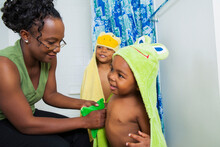 Mother Helping Boys Put On Hooded Towels After Bath