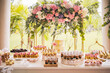 cake for the celebration of a first communion on a table full of desserts with decoration of roses