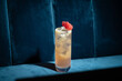 Cocktail on blue background. Modern, stylish drink placed on velvet couch at the bar, night club or restaurant. Refreshing alcoholic beverage with grapefruit and gin in highball glass. Copy space
