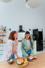 Two girlfriends cut fruit in the kitchen