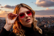 Beautiful Female Model Wearing Colorful Glasses At Sunset. Outdoors Romantic Portrait Of Attractive Blonde Woman With Makeup And Glasses Posing. Istanbul Archipelago (Princess Islands) Skyline.