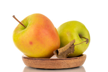 Two green sweet apples on a wooden plate, macro, isolated on white background.