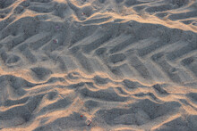 Abstract Background Beach Sand With Tire Marks And Sunlight Reflection