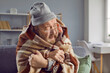 © Studio Romantic - Senior man freezing at home in winter. Elderly man wearing hat and wrapped in blanket sitting on sofa in chilly room with low temperature, in house with bad broken thermostat, in very cold wintertime