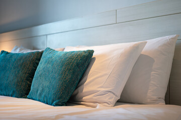 Green and white pillows set in contemporary design in the bedroom. Interior decoration and object photo, close-up and selective focus.