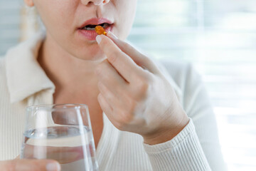 Wall Mural - Young woman taking Omega 3 capsule