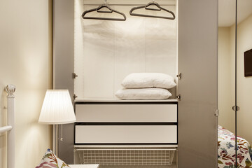 Room with open wardrobe with white wooden and mirror doors