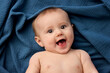 © Lisa Tichané - Smiling portrait of young baby lying on blue cotton gauze blanket