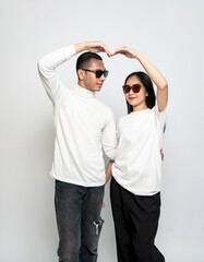 Wall Mural - Young couple wearing white blank shirt and glasses making a loving gesture with their hand