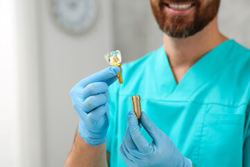 Sticker - Dentist holding educational model of dental implant on blurred background, closeup. Space for text