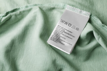 Sticker - Clothing label on pale olive garment, closeup