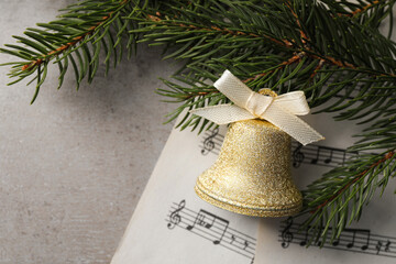 Sticker - Golden shiny bell with bow, music sheets and fir branches on light table, flat lay. Space for text. Christmas decoration