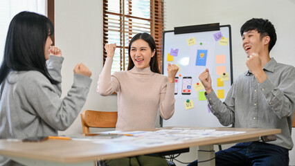 Canvas Print - cheerful and excited asian developers are celebrating their success together in the meeting room.