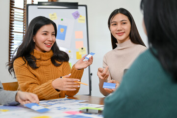 Canvas Print - beautiful asian female ui designer discussing and presenting her new prototype with her team