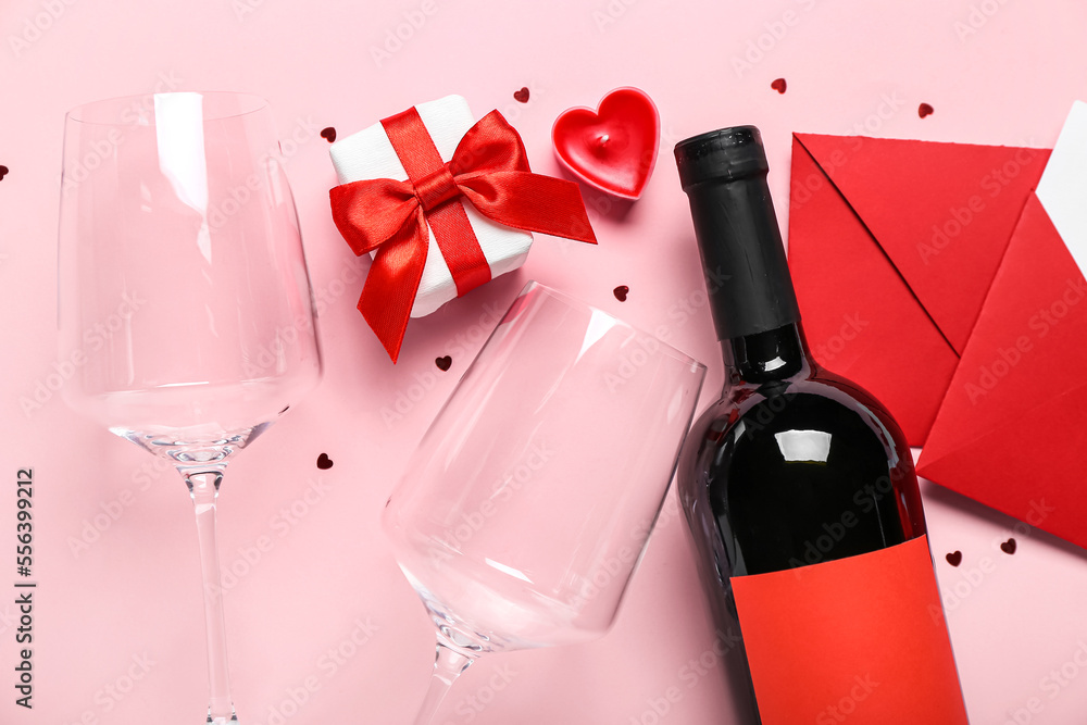 Envelopes with bottle of wine, gift and glasses on pink background. Valentine's Day celebration