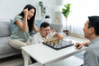 © Kawee - Asian attractive couple play chess game with their son in living room.