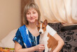 Indoor portrait of beautiful mature woman with basenji puppy