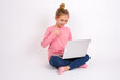 © Jihan - Young beautiful teen girl sitting over white studio background holding a laptop and making thumb up.