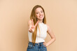 © Asier - Young redhead woman cut out isolated joyful and carefree showing a peace symbol with fingers.