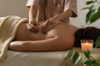 © Volha - Masseur does a back massage in the cozy atmosphere of the spa salon with green plants, a burning candle. Concept of a healthy lifestyle and body care.