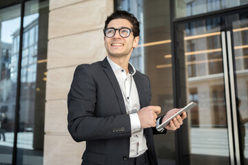 The economist is a man in a business suit, smiling, going to the office. Uses a tablet to read a blog in the business app.