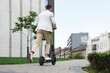 © New Africa - Businessman riding modern kick scooter on city street, back view. Space for text