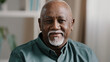 Close up portrait at home male headshot calm elderly senior adult African 60s man face indoors looking at camera. Old retired businessman CEO posing in office. Bald grandfather look close up smile