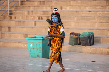 Wall Mural - Portrait of a young boy dress up like lord shiva with painted blue face near river ganges ghat in varanasi city.