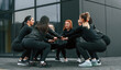 © standret - Conception of teamwork. Group of sportive women is outdoors near black building