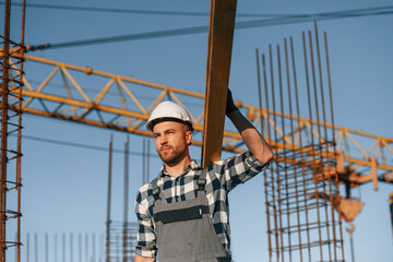 Wall Mural - Against crane. With wooden plank. Man is working on the construction site at daytime