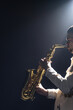 © puhimec - A European man plays the saxophone in the dark.