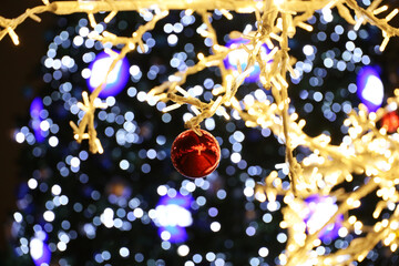 Wall Mural - Festive lights on background of Christmas tree. New Year decorations on winter street