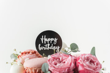 Canvas Print - Birthday cake with white cream cheese frosting decorated with red roses and pink macaroons on the white background. Happy birthday topper on anniversary cake