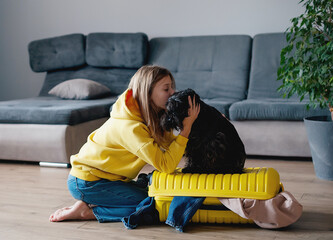 Wall Mural - girl is packing her suitcase. Yellow plastic travel bag. The girl collects clothes for a trip. Journey concept.