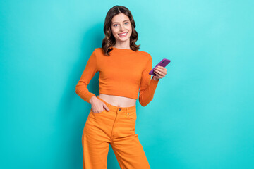 Wall Mural - Photo of adorable lovely lady wear trendy orange clothes hold modern gadget telephone iphone samsung isolated on cyan color background