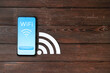 © Pixel-Shot - Mobile phone with WiFi symbol and connection button on wooden background