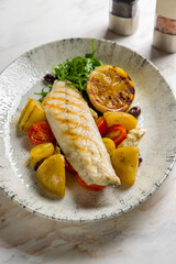 Wall Mural - sea bass fillet with grilled vegetables and lemon on marble table vertical