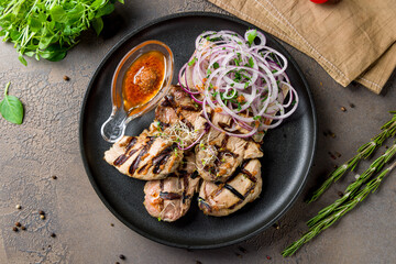 Poster - Kebab of pork with red onion and tomato sauce on black plate top view