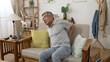 © PRPicturesProduction - Asian senior Korean man having back pain and walking by sofa while hands holding chair arms. medical and healthcare concept