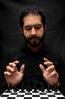 © Narayan - latin man with beard manipulating the pieces of the board, chess concept