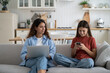 © DimaBerlin - Parental monitoring of adolescents. Curious mother spying teenage daughter looking child text messages on smartphone. Mom and kid using gadgets, resting on sofa at home. Family and modern technologies