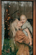 © Westend61 - Mother kissing baby boy seen through window at home