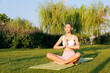 © Westend61 - Woman with eyes closed practicing padmasana pose on exercise mat in park